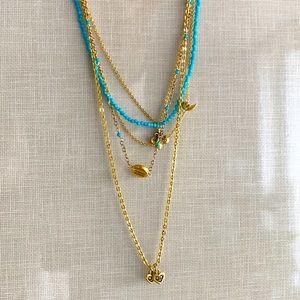 Gold charm necklace with turquoise beads.